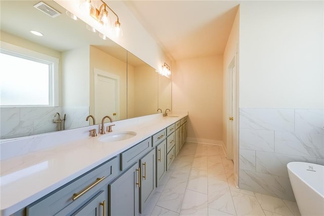 full bath with double vanity, visible vents, a sink, marble finish floor, and tile walls