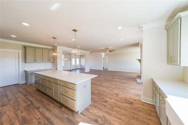 kitchen featuring pendant lighting, light countertops, crown molding, and a center island