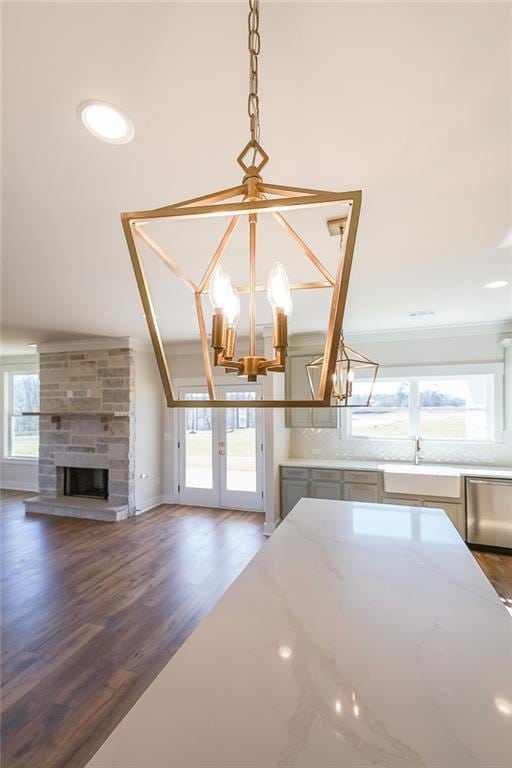 kitchen with dishwasher, light stone counters, an inviting chandelier, french doors, and a sink