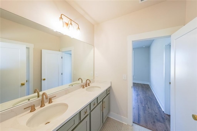 bathroom featuring double vanity, a sink, and baseboards