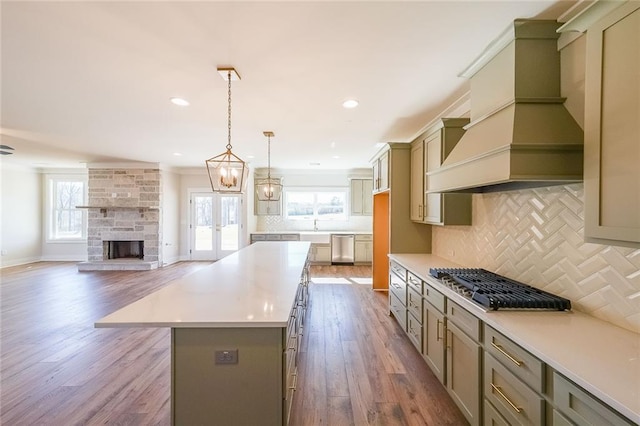 kitchen featuring a center island, hanging light fixtures, light countertops, stainless steel appliances, and premium range hood