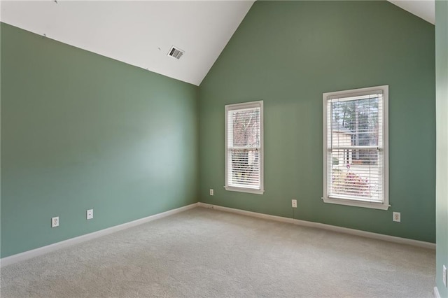 carpeted spare room with a wealth of natural light, visible vents, high vaulted ceiling, and baseboards