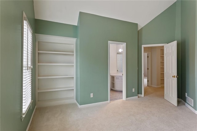 unfurnished bedroom with lofted ceiling, multiple windows, and carpet