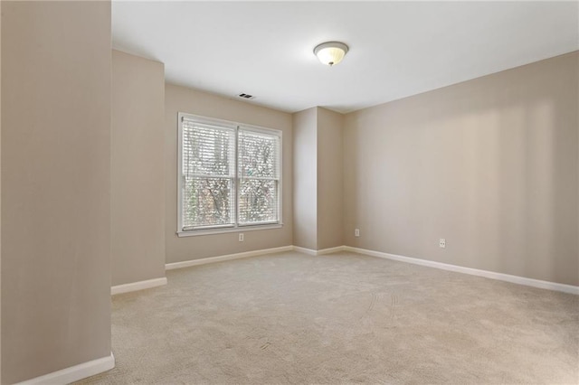 carpeted spare room featuring baseboards and visible vents