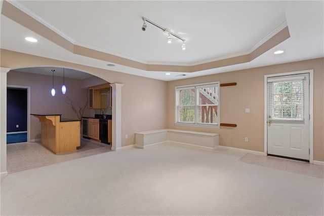 unfurnished living room featuring a tray ceiling, decorative columns, light colored carpet, and plenty of natural light