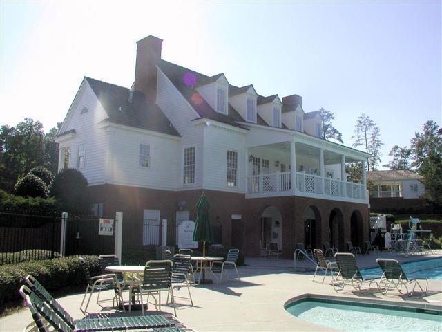 back of property with a balcony, fence, a chimney, a community pool, and a patio area