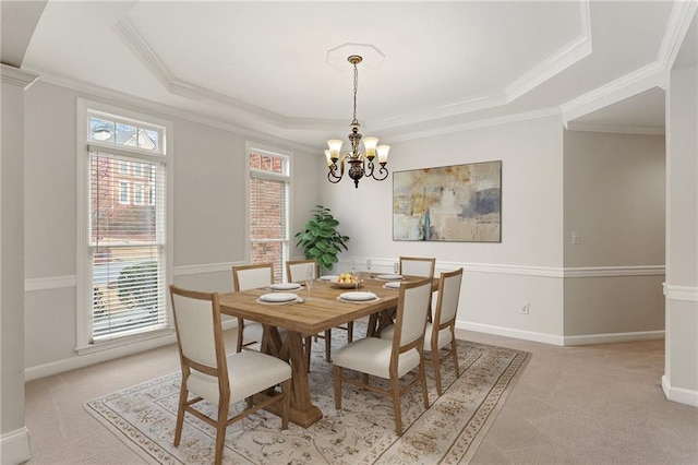 dining room featuring baseboards, ornamental molding, light carpet, an inviting chandelier, and a raised ceiling