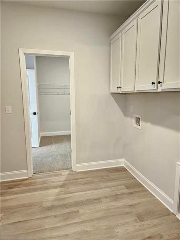 1695 Crumbley Rd, Mcdonough, GA 30252 - laundry area with baseboards, cabinet space, and light wood-style flooring