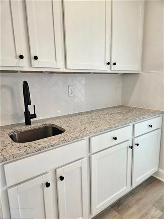 1695 Crumbley Rd, Mcdonough, GA 30252 - kitchen featuring a sink, light wood-style floors, white cabinetry, and tasteful backsplash