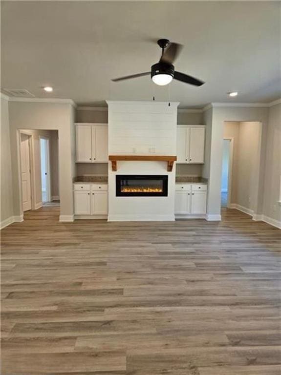 1695 Crumbley Rd, Mcdonough, GA 30252 - unfurnished living room with baseboards, ornamental molding, recessed lighting, light wood-type flooring, and a glass covered fireplace