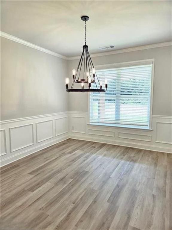 1695 Crumbley Rd, Mcdonough, GA 30252 - unfurnished dining area featuring a chandelier, wainscoting, wood finished floors, ornamental molding, and a decorative wall