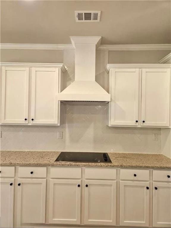 1695 Crumbley Rd, Mcdonough, GA 30252 - kitchen with custom exhaust hood, white cabinetry, black electric stovetop, and crown molding