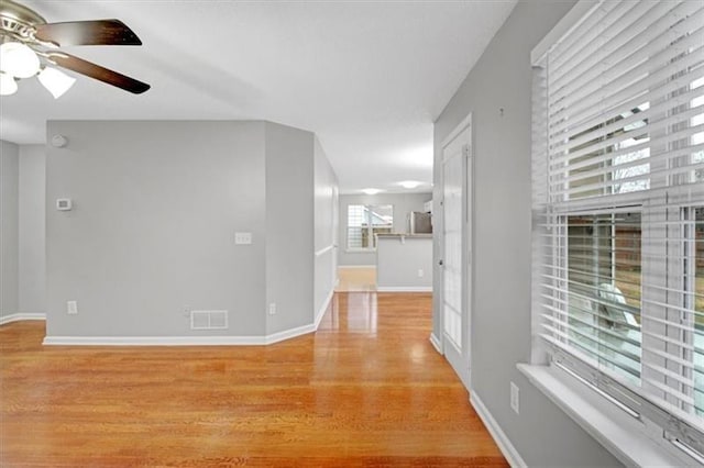 hall featuring visible vents, baseboards, and light wood-style flooring