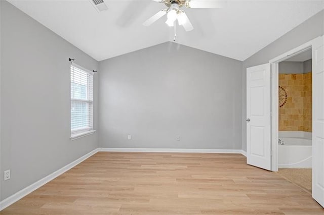 empty room featuring light wood-type flooring, baseboards, lofted ceiling, and visible vents