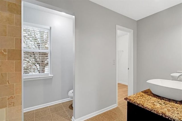 bathroom featuring vanity, toilet, and baseboards