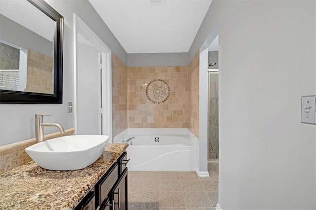 full bath with a stall shower, baseboards, a bath, and vanity