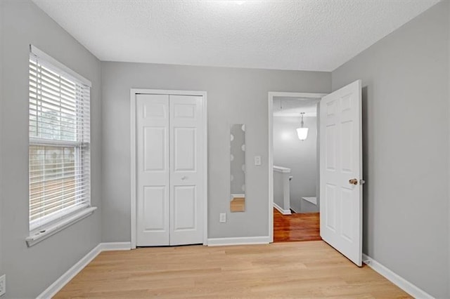 unfurnished bedroom featuring a closet, baseboards, and light wood-style floors