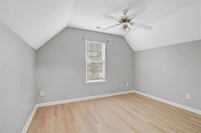 bonus room with vaulted ceiling, wood finished floors, baseboards, and a textured ceiling