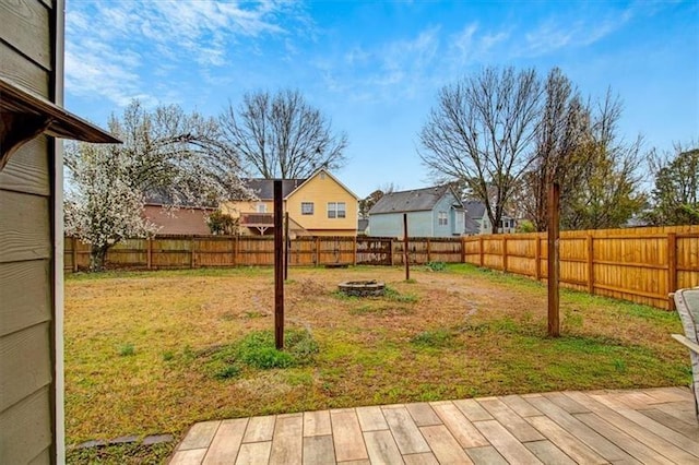 view of yard featuring a residential view, a fire pit, and a fenced backyard