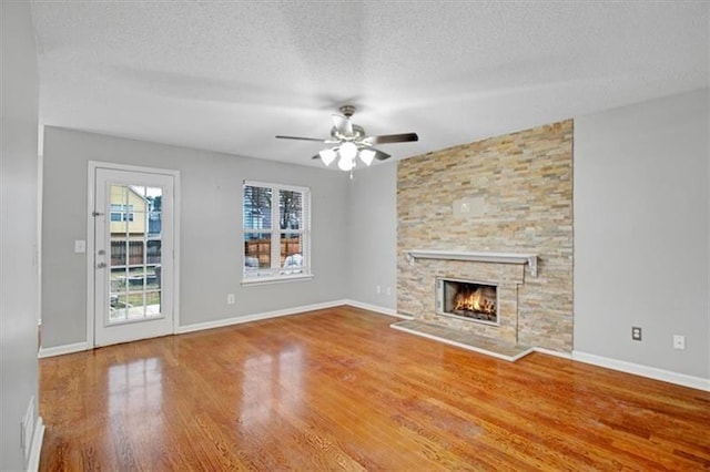 unfurnished living room featuring baseboards, a textured ceiling, wood finished floors, and a fireplace