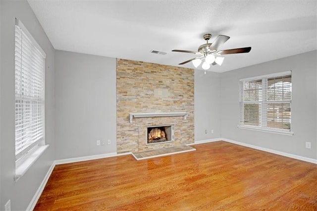 unfurnished living room featuring visible vents, baseboards, wood finished floors, and a fireplace