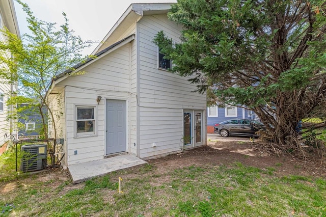 rear view of property with a lawn and central air condition unit