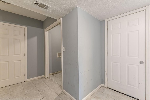 hall with light tile patterned flooring and a textured ceiling