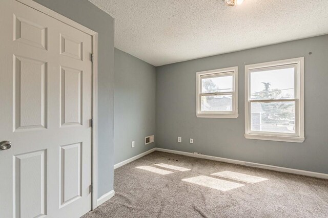 carpeted spare room with a textured ceiling