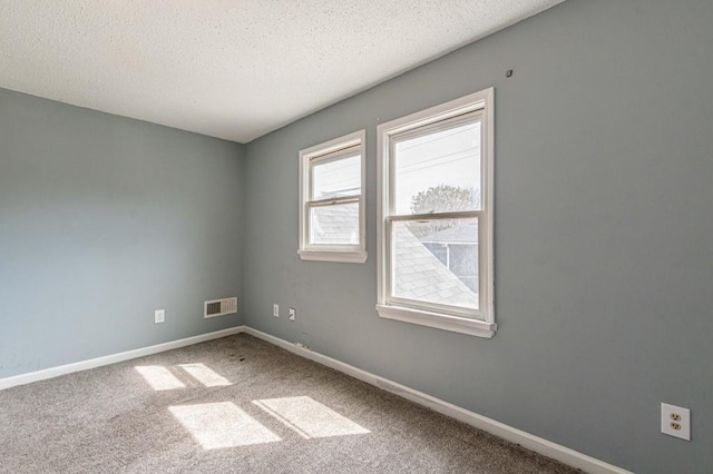 empty room with a textured ceiling and carpet floors