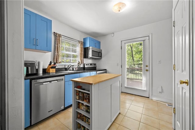 511 Robinson Ave SE, Atlanta, GA 30315 - kitchen with stainless steel appliances, blue cabinets, wood counters, a sink, and light tile patterned floors