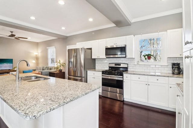 kitchen featuring stainless steel appliances, a kitchen island with sink, sink, and white cabinets