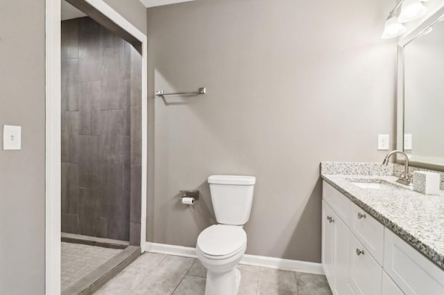 bathroom featuring vanity, tile patterned flooring, toilet, and tiled shower