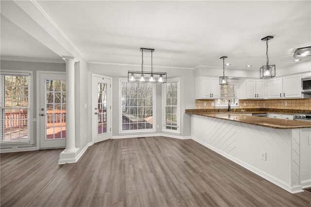 kitchen featuring decorative light fixtures, white cabinets, kitchen peninsula, and backsplash