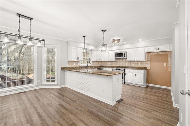 kitchen with stainless steel appliances, white cabinets, decorative light fixtures, and kitchen peninsula