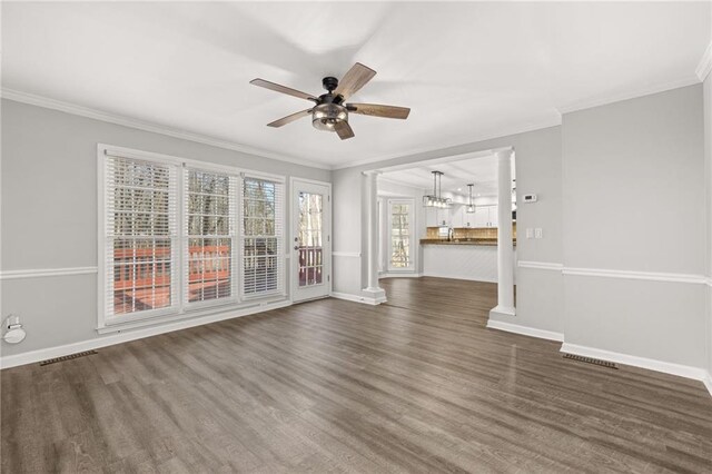 unfurnished living room with crown molding, dark hardwood / wood-style floors, decorative columns, and ceiling fan with notable chandelier