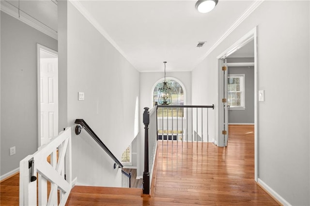 stairs featuring ornamental molding, hardwood / wood-style flooring, and a notable chandelier