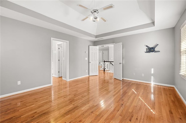 unfurnished bedroom with a raised ceiling, ceiling fan, and wood-type flooring