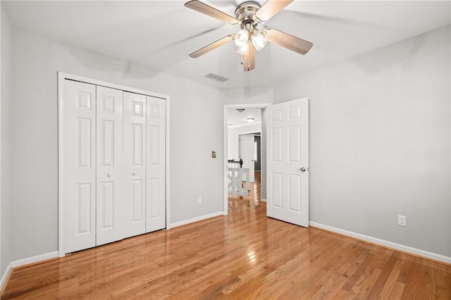 unfurnished bedroom featuring ceiling fan, light wood-type flooring, and a closet