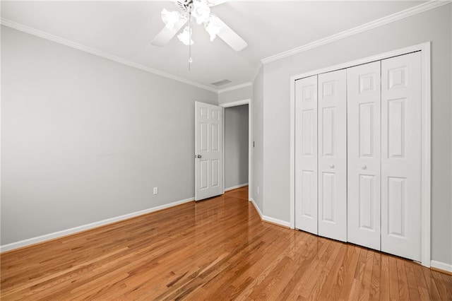 unfurnished bedroom featuring ceiling fan, light hardwood / wood-style flooring, ornamental molding, and a closet