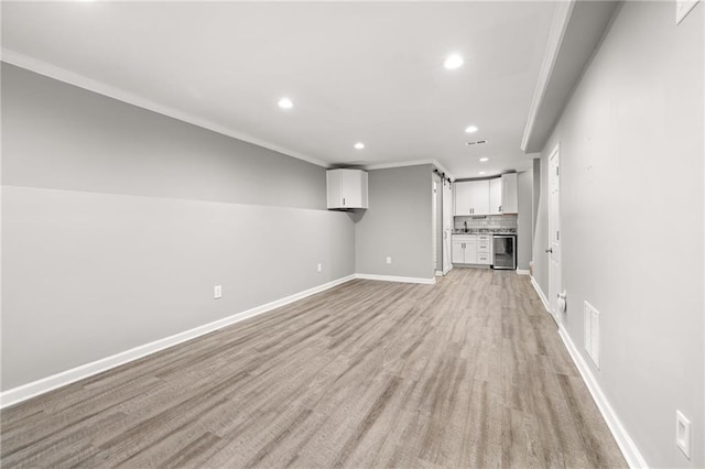 unfurnished living room featuring light wood-type flooring, wine cooler, and crown molding