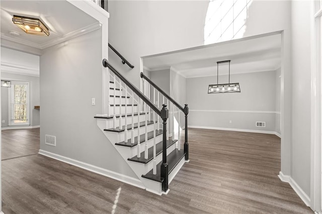 stairway with ornamental molding and hardwood / wood-style flooring