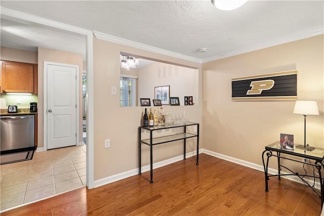 corridor with crown molding, a textured ceiling, and light wood-type flooring