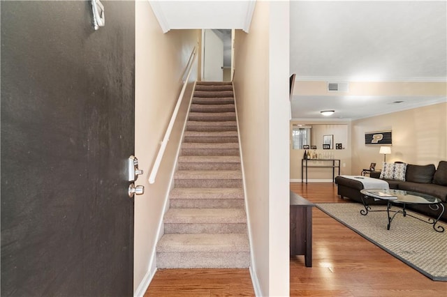 stairs featuring hardwood / wood-style flooring and ornamental molding