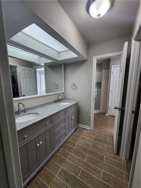 bathroom with oversized vanity, dual sinks, a skylight, and tile flooring