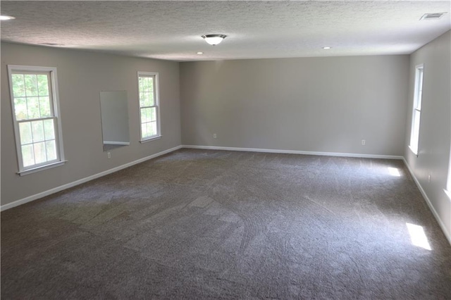 empty room with a wealth of natural light and dark colored carpet