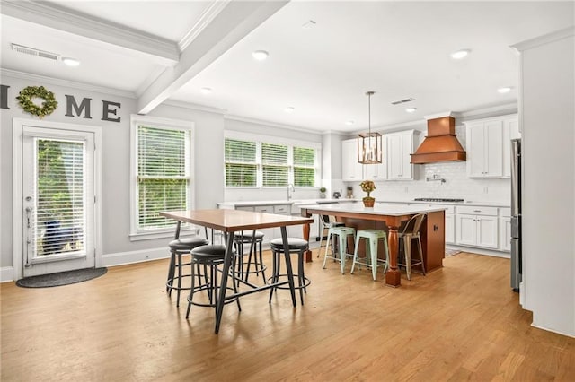 dining area with ornamental molding, light wood-style floors, baseboards, recessed lighting, and beam ceiling