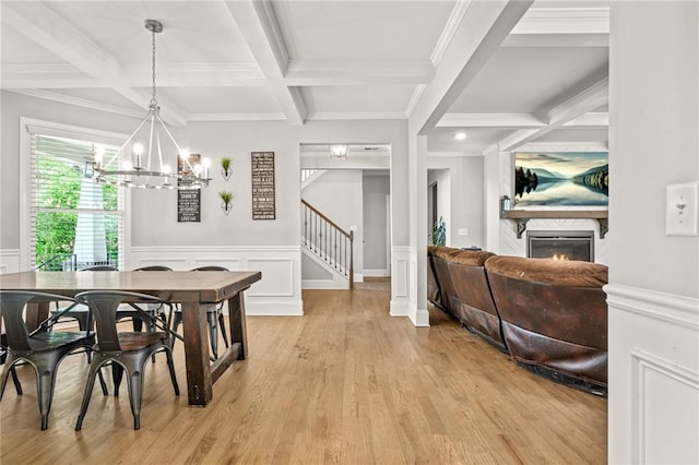 dining room featuring coffered ceiling, stairs, a chandelier, a glass covered fireplace, and beamed ceiling