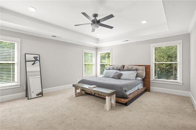 carpeted bedroom featuring a raised ceiling, crown molding, baseboards, and a ceiling fan