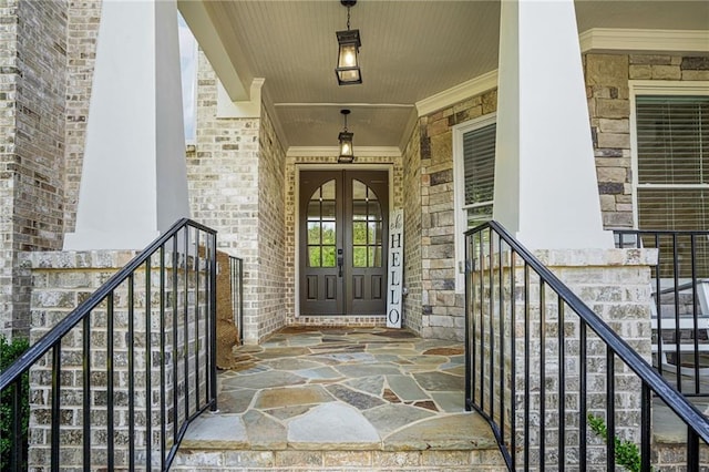 entrance to property with french doors, a porch, stone siding, and brick siding