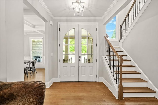 foyer entrance with stairs, light wood-style flooring, plenty of natural light, french doors, and ornamental molding